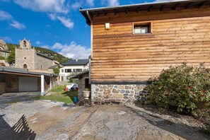 A rustic wooden building with a stone foundation, a small window, and a stone tower in the background. - Peaceful stay in the heart of a mountain village, with views of the pyrenees. (Égat)