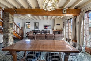 A spacious living area with a wooden dining table, leather sofas, and a stone pillar. - Peaceful stay in the heart of a mountain village, with views of the pyrenees. (Égat)