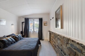 Un dormitorio con cama, un radiador, una ventana con cortinas y un cuadro en la pared.