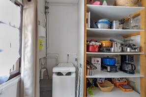 A compact kitchen with a washing machine, a coffee maker, and various kitchen utensils on shelves. - Peaceful stay in the heart of a mountain village, with views of the pyrenees. (Égat)
