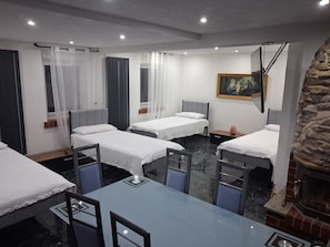 A hotel room with two single beds, a glass table, and a stone fireplace. - Forest House with Private Terrace (Sugenheim)