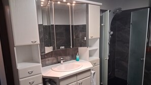 A modern bathroom with a vanity, mirror, and shower. - Forest House with Private Terrace (Sugenheim)