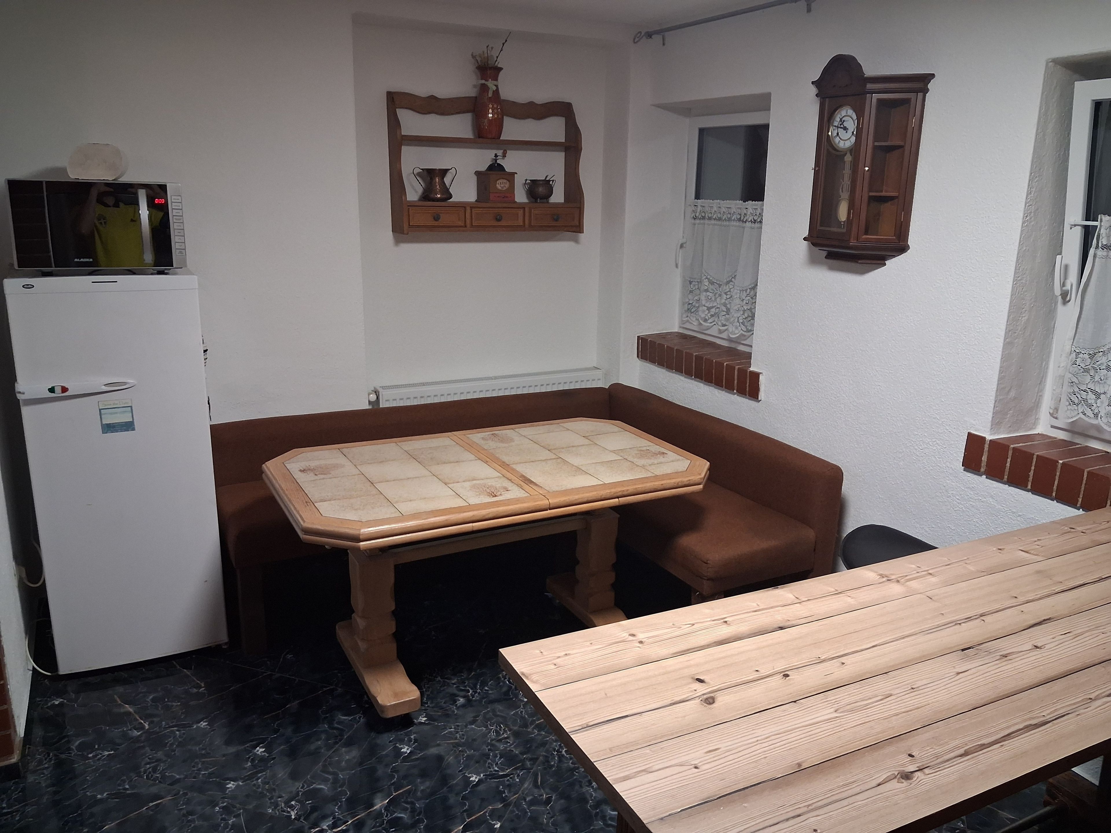 Une cuisine compacte comprenant un réfrigérateur, une table en bois et un meuble contenant des ustensiles de cuisine.