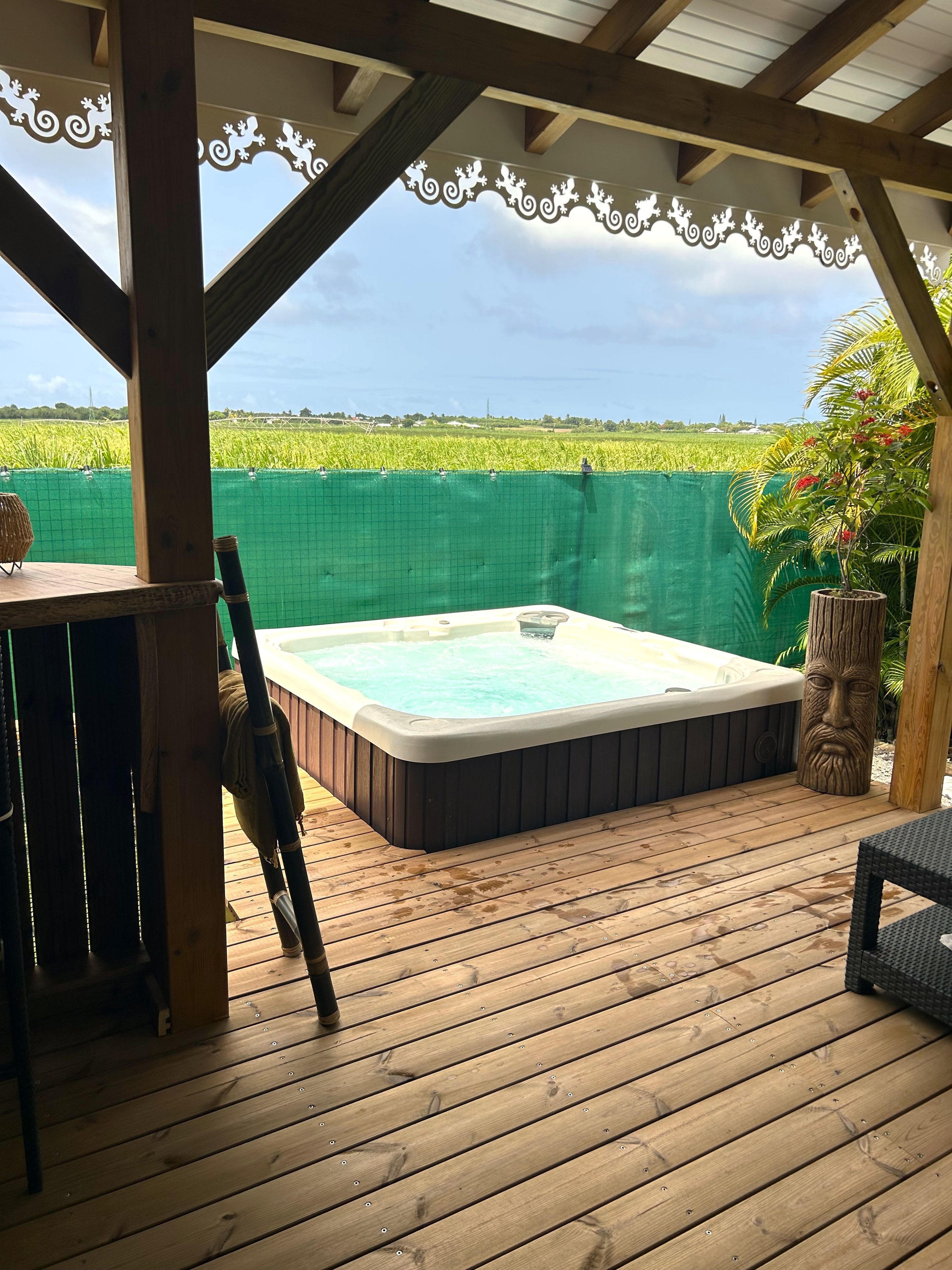 Une terrasse en bois avec un jacuzzi, une table et des chaises.
