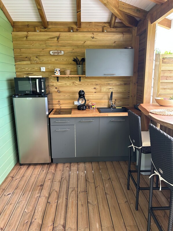 A compact kitchen with a microwave, coffee maker, and sink.