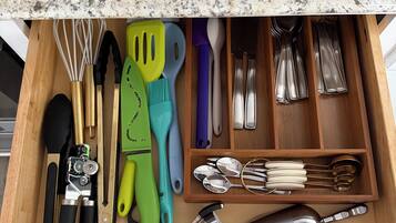 A drawer with kitchen utensils and tools, including whisks, spatulas, and measuring spoons.