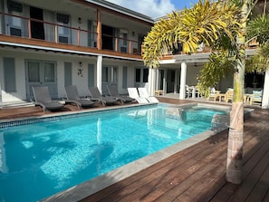 Ein Poolbereich mit Liegestühlen und einer Holzterrasse.