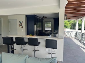 Cocina moderna con una isla central, taburetes de bar y un comedor con un sofá de tonos claros.