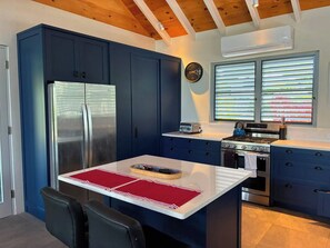 Eine moderne Küche mit blauen Schränken, einem Edelstahl-Kühlschrank, einem Gasherd und einem eingebauten Backofen.