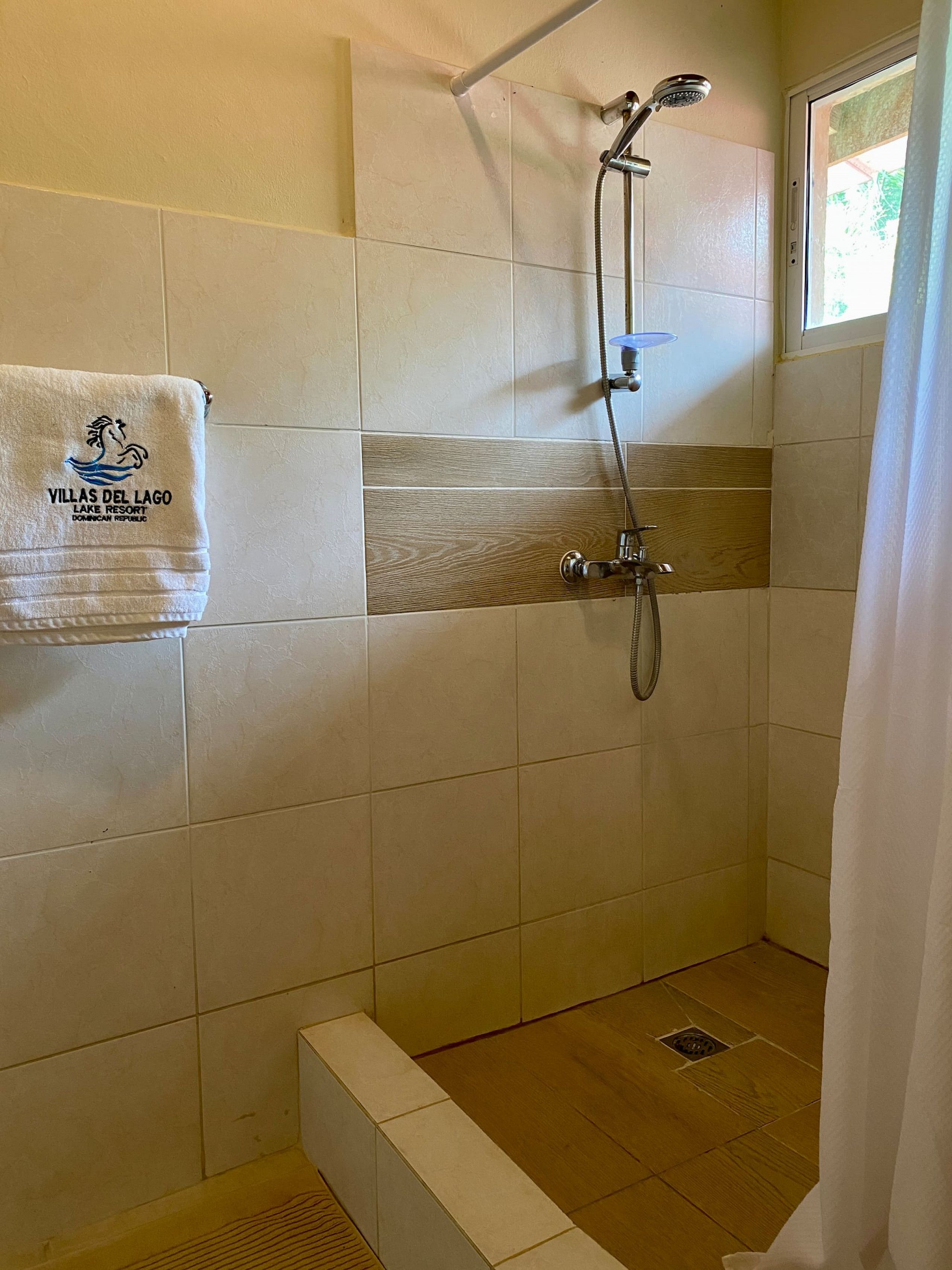 A shower area with a tiled wall, a showerhead, and a towel hanging on the wall.