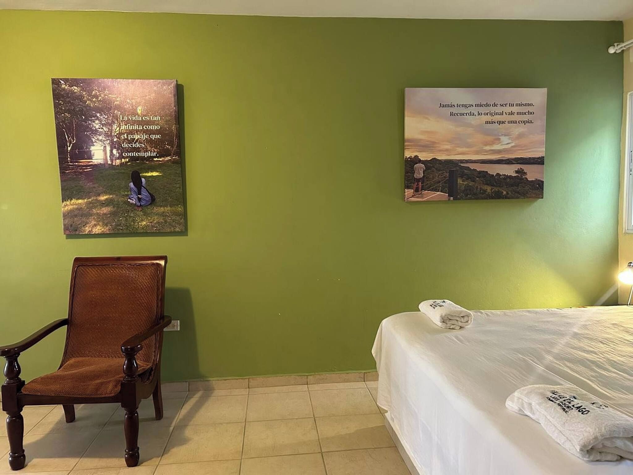 Een hotelkamer met een bed, een stoel en twee kunstwerken aan de muur.