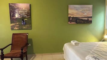 Een hotelkamer met een bed, een stoel en twee kunstwerken aan de muur.
