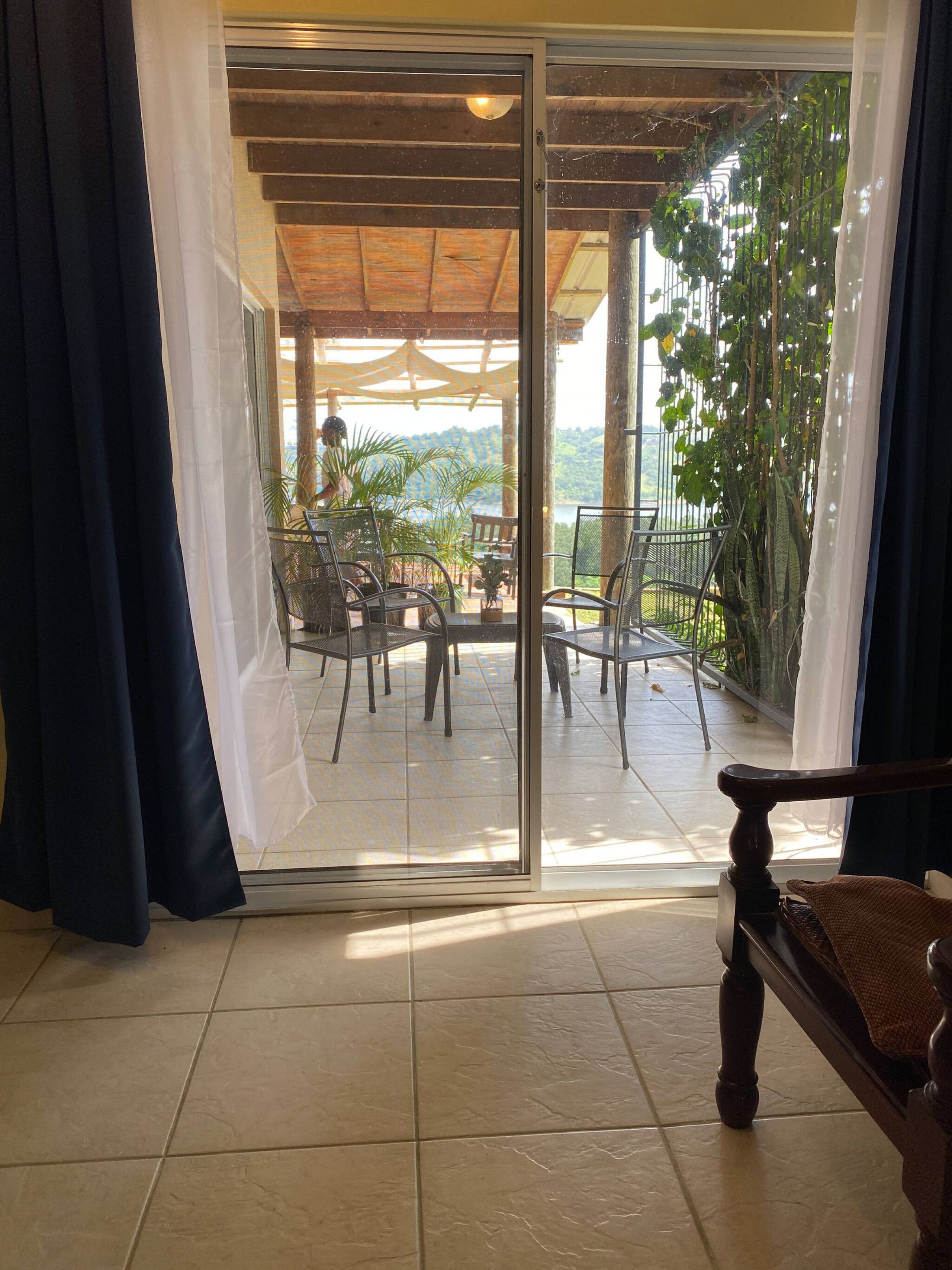 A room with a sliding glass door leading to an outdoor patio area with chairs and tables.