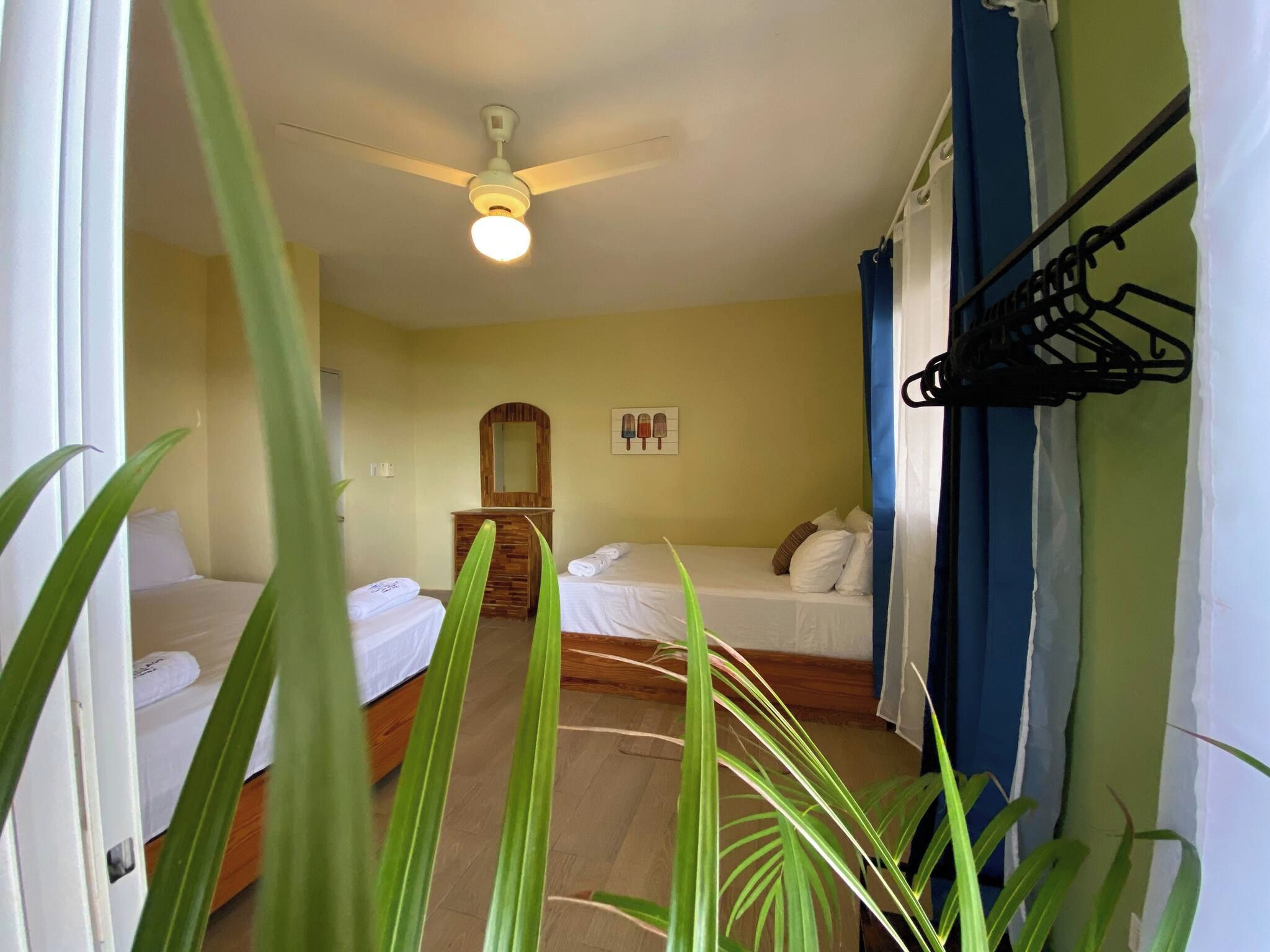 A hotel room with two beds, a ceiling fan, a wooden dresser, and a mirror.