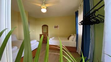 A hotel room with two beds, a ceiling fan, a wooden dresser, and a mirror.