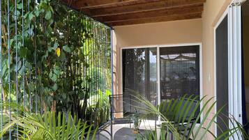 A covered outdoor area with a metal fence, a chair, and a table.