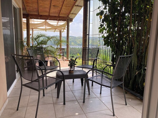Un espacio de estar al aire libre cubierto con sillas de metal y una mesa, con vistas a un paisaje pintoresco.