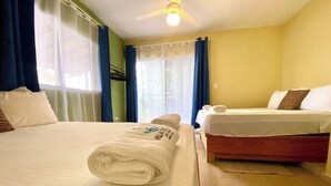 Ein Hotelzimmer mit zwei Betten, einem Deckenventilator und einem Fenster mit Vorhängen.