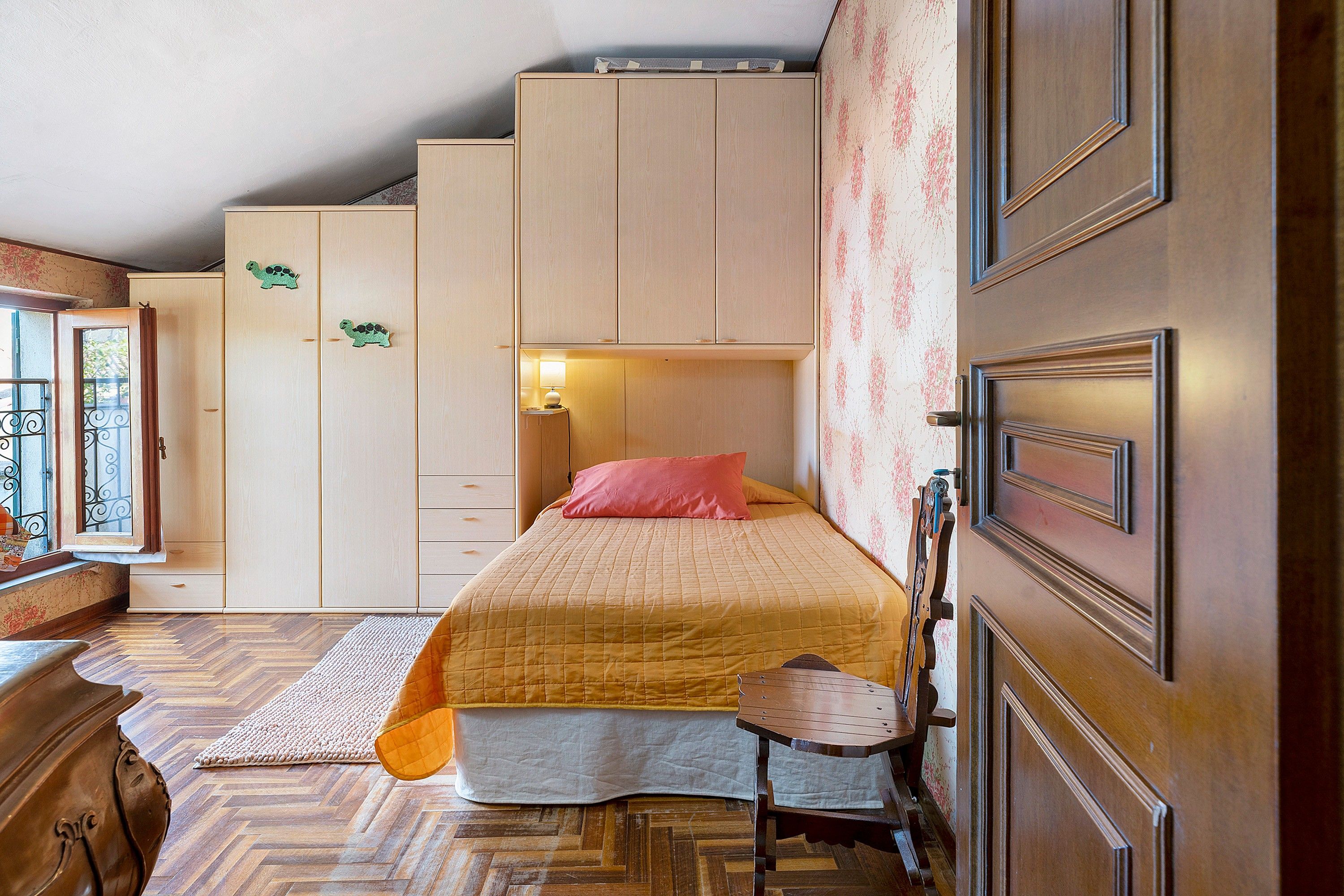Una camera da letto con un letto, una cassettiera, un comodino e una finestra con tende.