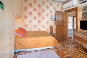A bedroom with a bed, a dresser, a television, and a door leading to another room. - Room 'Camera Singola' with Wi-Fi (Grosseto)