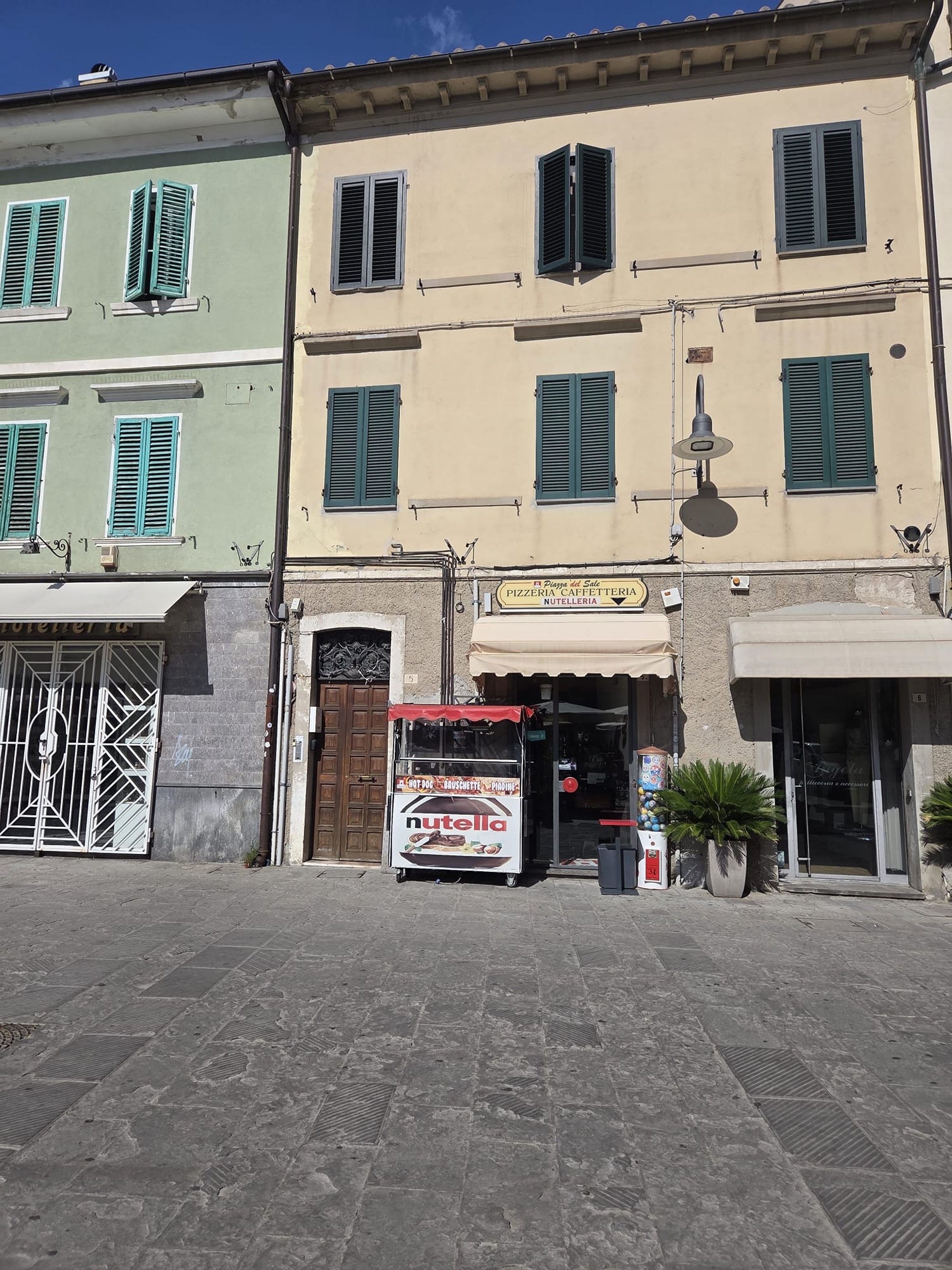 A street with buildings, a storefront with a sign for a cafe, and a vending machine.