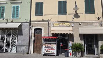 A street with buildings, a storefront with a sign for a cafe, and a vending machine.