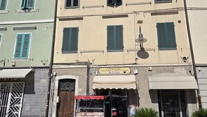 A street view with a row of buildings, a storefront with a sign for a pizzeria, and a parked food truck. - Room 'Camera Matrimoniale' with Wi-Fi and Air Conditioning (Grosseto)