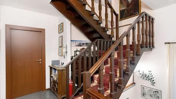 A wooden staircase with a red carpeted landing, a closed wooden door, and a wall with framed pictures and a clock.