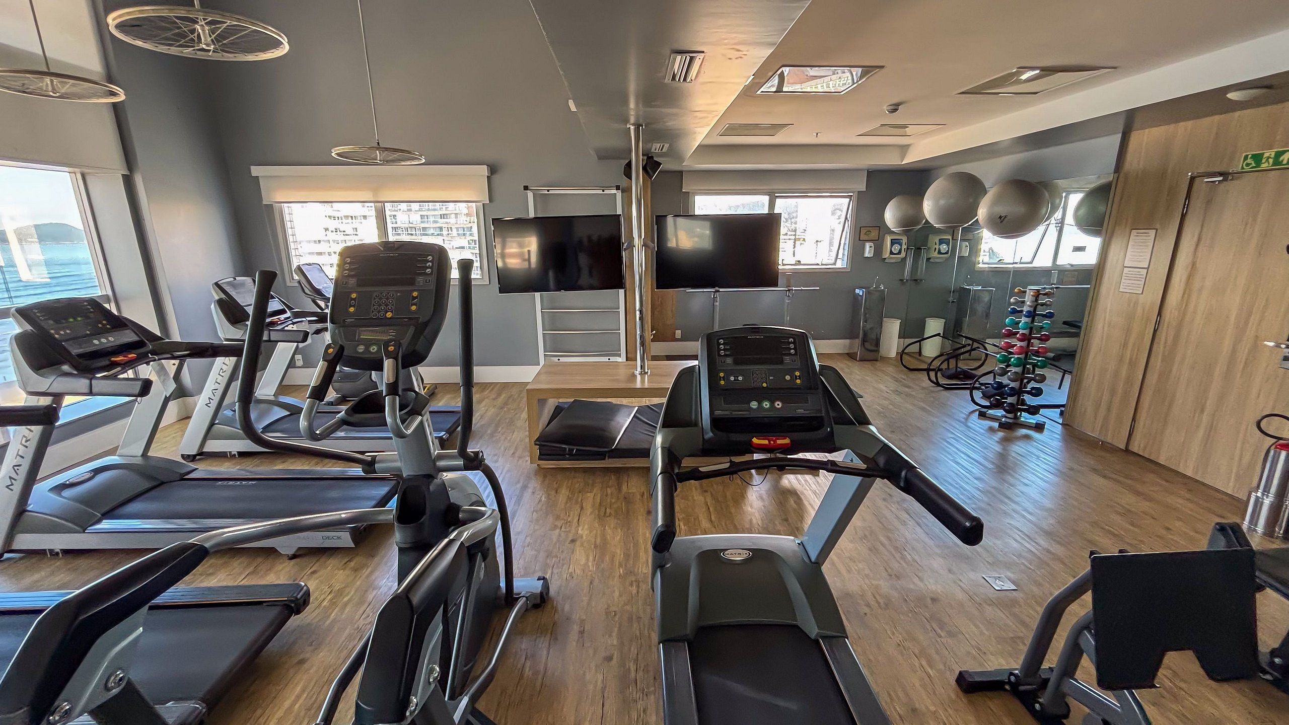 Un gimnasio con cintas de correr, bicicletas estáticas y una estructura para pesas.