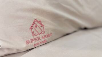 Ein Kissen mit aufgesticktem Text 'SUPER HOST BRASIL' auf hellem Stoff.