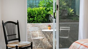En balkon med stol, bord og en potteplante.