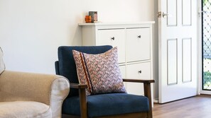 A room with a blue armchair, a patterned pillow, a white cabinet, and a door with a window. - Shoal Villa in Shoalhaven Heads (Shoalhaven Heads)