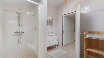 Een moderne badkamer met een douche, een wastafel en een houten bankje.