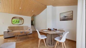 Een modern interieur met een houten plafond, een ronde eettafel met stoelen, een bank en een schilderij aan de muur.