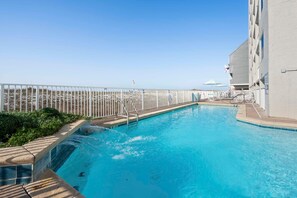 A swimming pool with a white fence, a lifeguard stand, and a view of the ocean. - Castaways 4A (Gulf Shores)