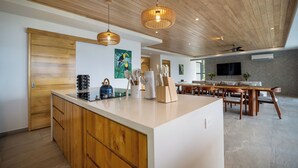 A modern kitchen with wooden cabinetry, a central island, and pendant lighting. - Modern family friendly, ocean view house near Dominical - Wi-Fi, inifinity pool (Dominical)