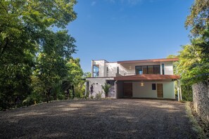 A modern two-story house with a gravel driveway, surrounded by lush greenery. - Modern family friendly, ocean view house near Dominical - Wi-Fi, inifinity pool (Dominical)
