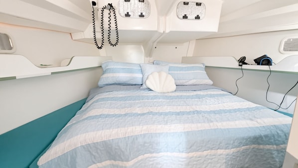 Una cama con ropa de cama a rayas, un cojín en forma de concha blanca y un cabecero con iluminación integrada.