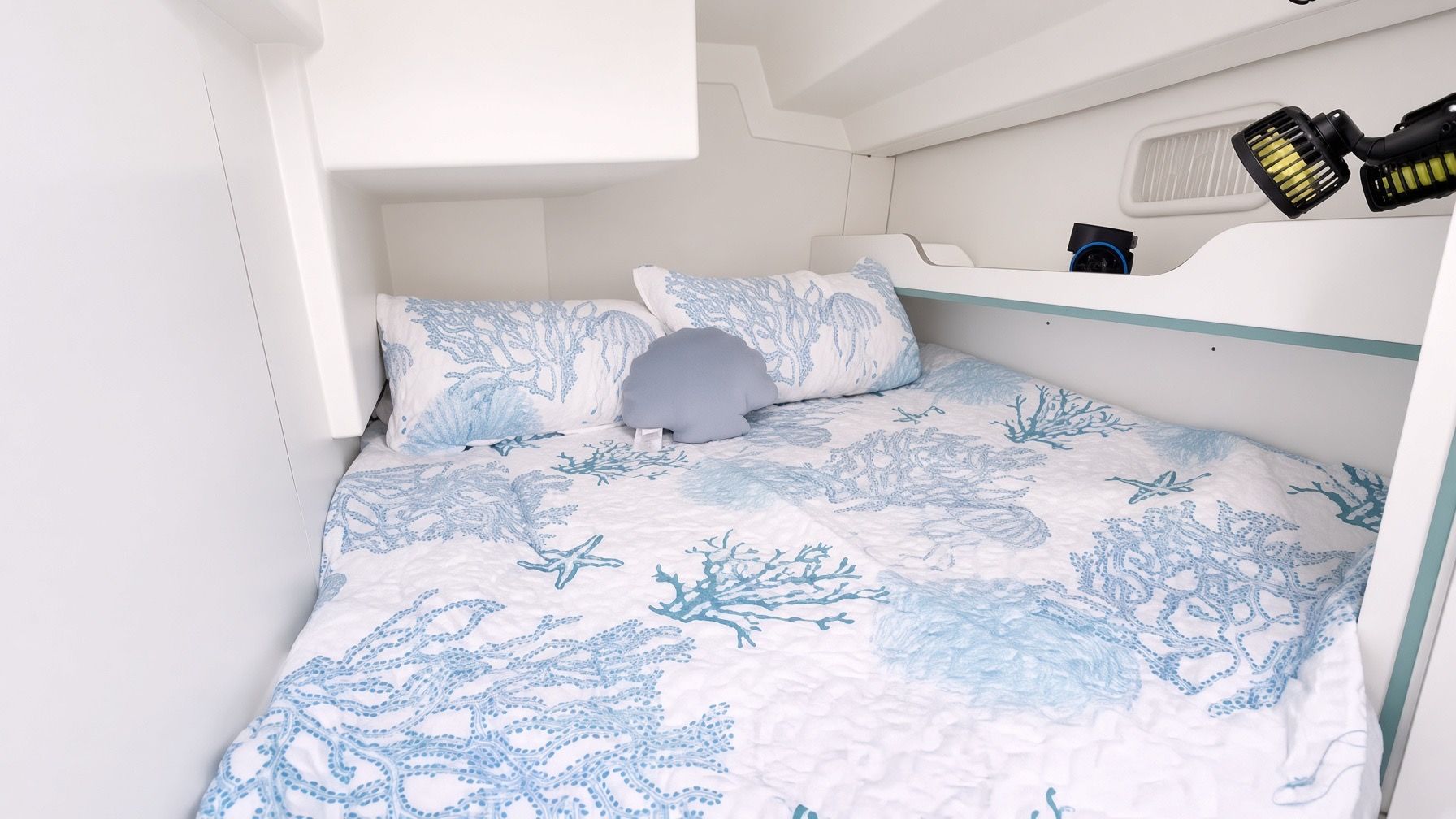 Een stapelbed met beddengoed in een blauw-wit, oceaan-thema.