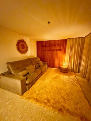 Un salón acogedor con un sofá, una alfombra, un adorno circular en la pared y una puerta de madera.