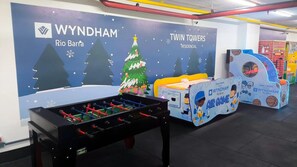 A foosball table and an air hockey table in a recreational area with a backdrop of a winter-themed mural.