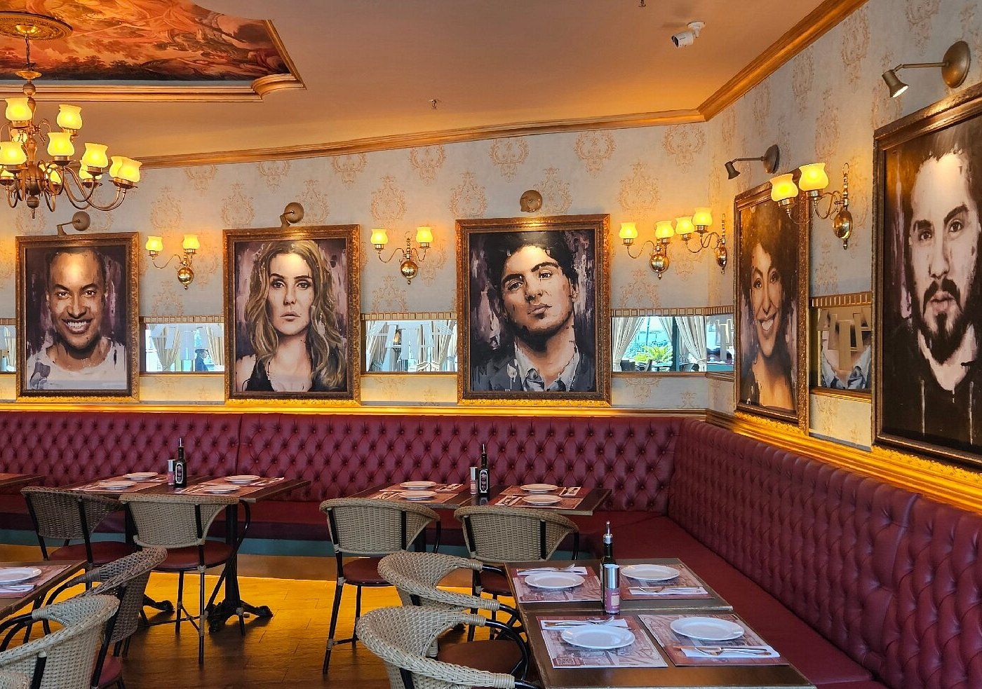 Een restaurantinterieur met rode bekleden banken, rieten stoelen en gedekte tafels.
