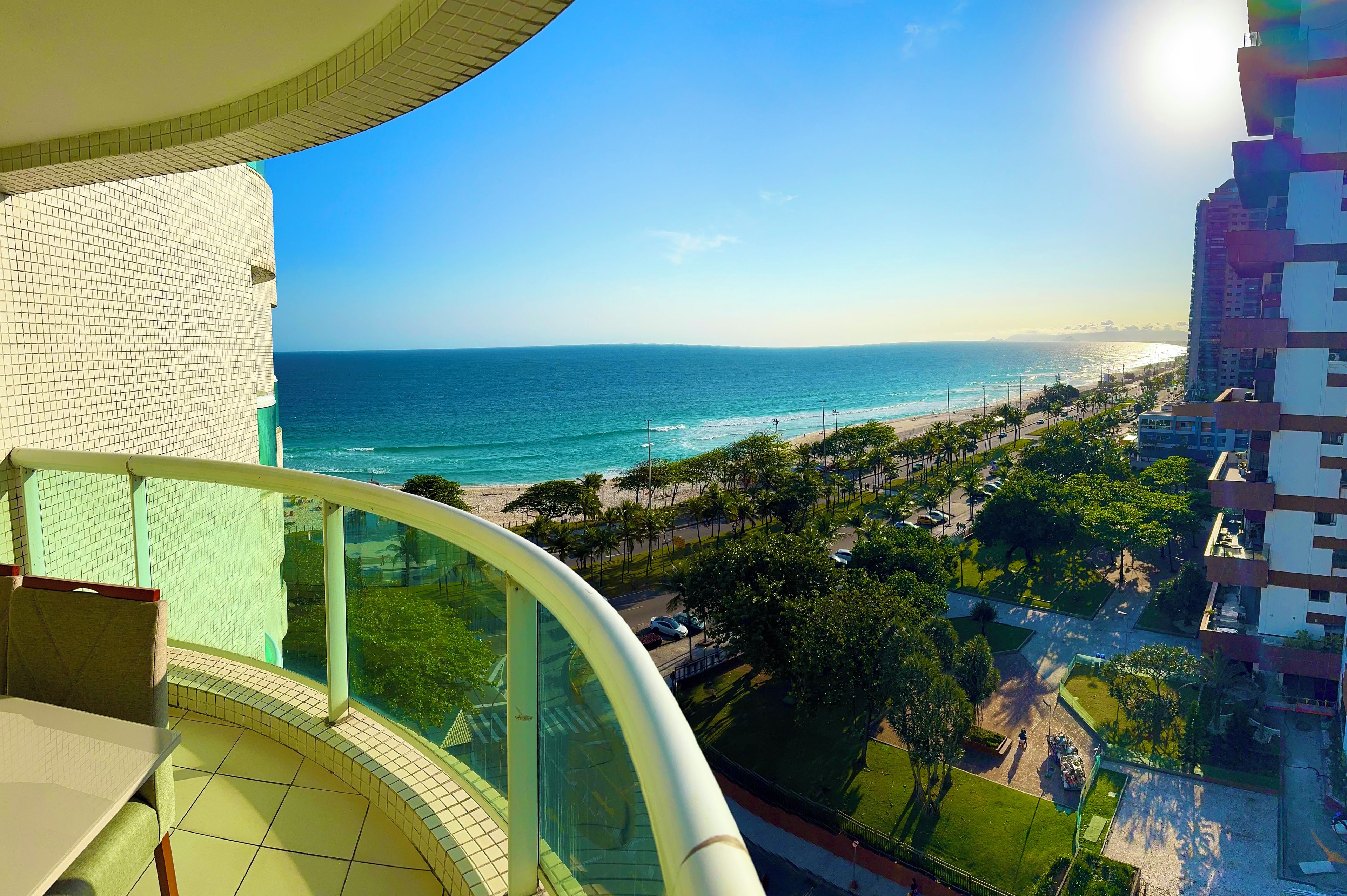 Um edifício alto com varanda curva, com vista para uma praia e oceano.
