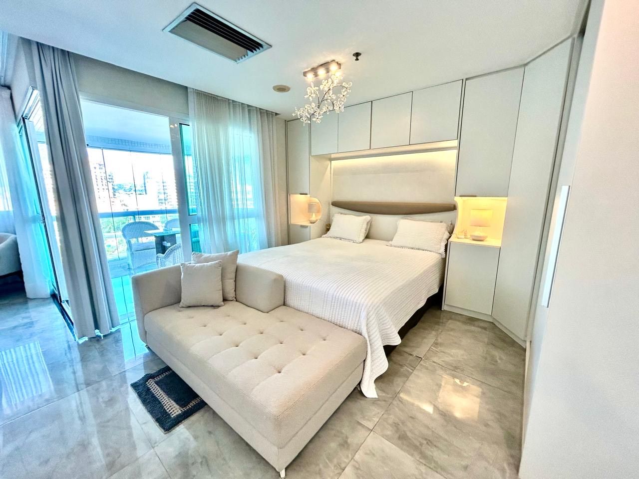 A modern bedroom with a large bed, a sofa, and a view of the outdoors.
