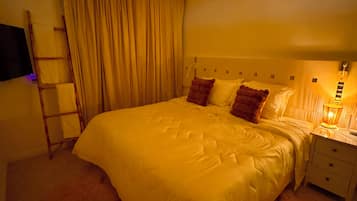 A bedroom with a large bed, a nightstand, a lamp, a ladder, and a curtain.