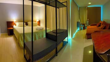 A hotel room with a bed, a seating area, a table, and a TV.