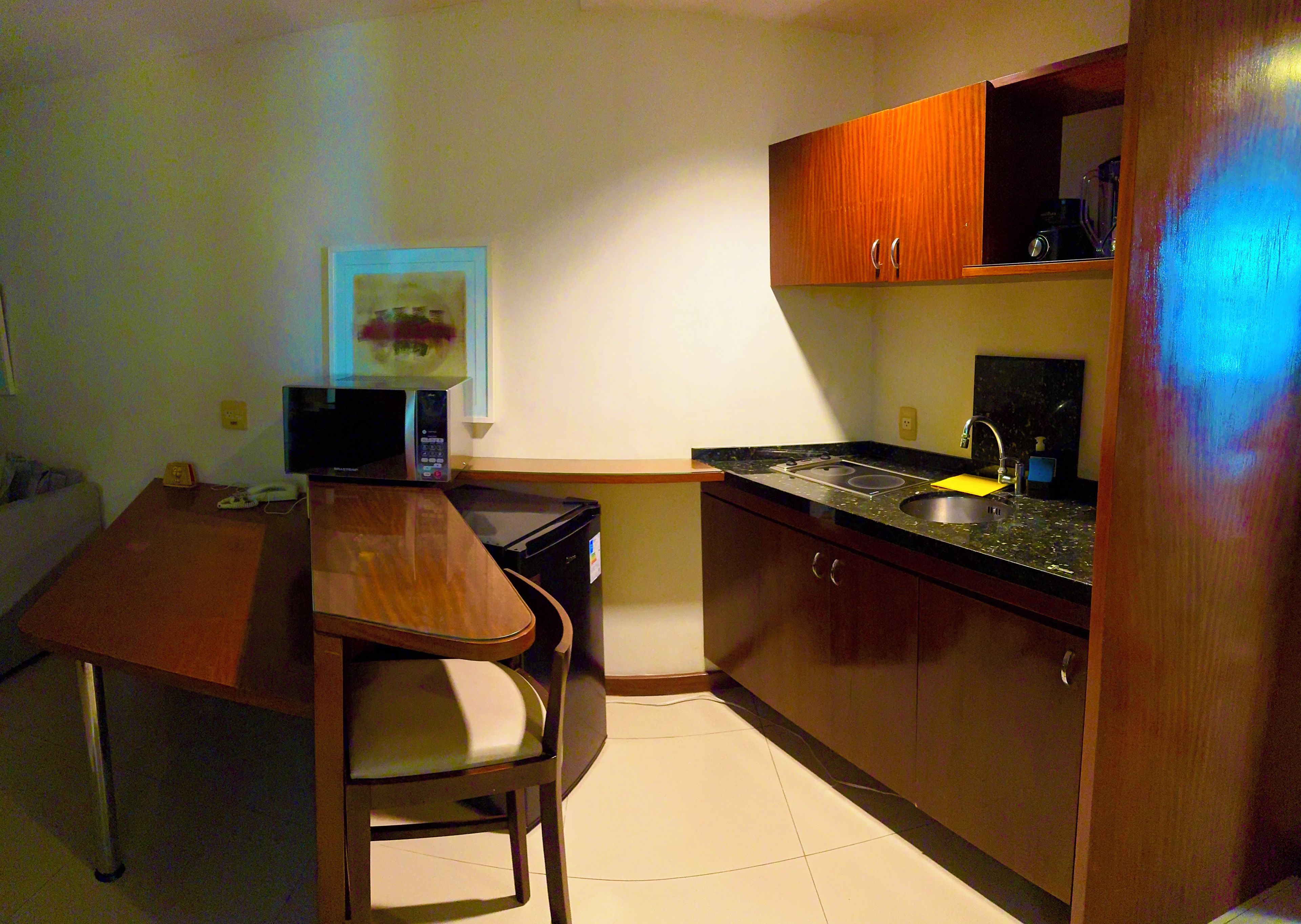 A compact kitchen with a microwave, a small sink, and wooden cabinets.