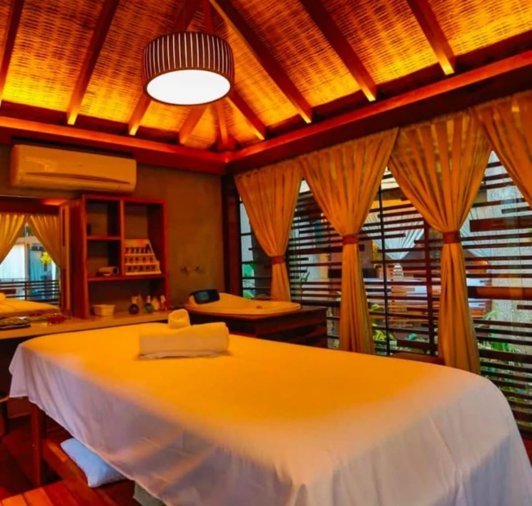 Quarto de hotel com cama, escrivaninha e janela com cortinas.