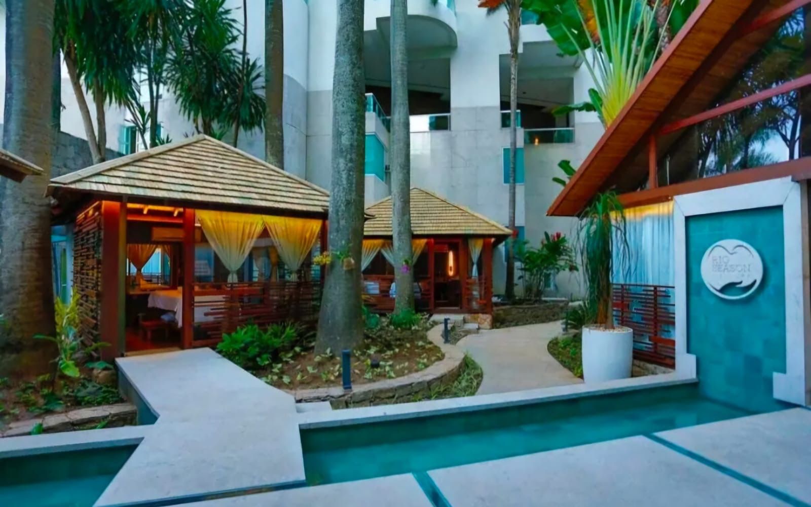 A resort with outdoor seating areas, a swimming pool, and a building with a sign.