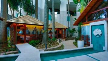 A resort with outdoor seating areas, a swimming pool, and a building with a sign.